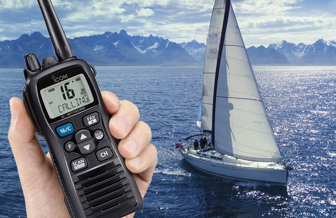 Hand houdt een Icom-handheld radio (model IC-M73EURO) met actief kanaal 16 vast, op de achtergrond een zeilboot op open zee bij zonnig weer. Hand houdt een Icom-handheld radio (model IC-M73EURO) met actief kanaal 16 vast, op de achtergrond een zeilboot op open zee bij zonnig weer.