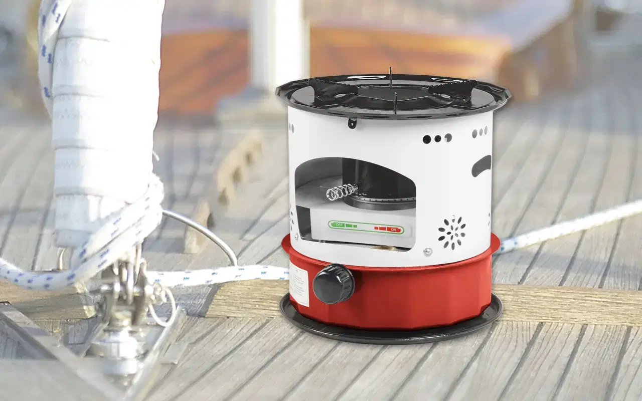 Compacte, draagbare gasfornuis met een rode behuizing en een zwarte draaiknop, geplaatst op een houten dek, ideaal voor gebruik op boten of tijdens het kamperen.